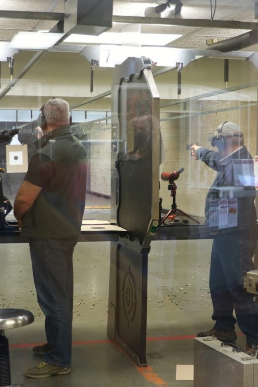 Four olympic-style pistol competitors taking aim on indoor range
