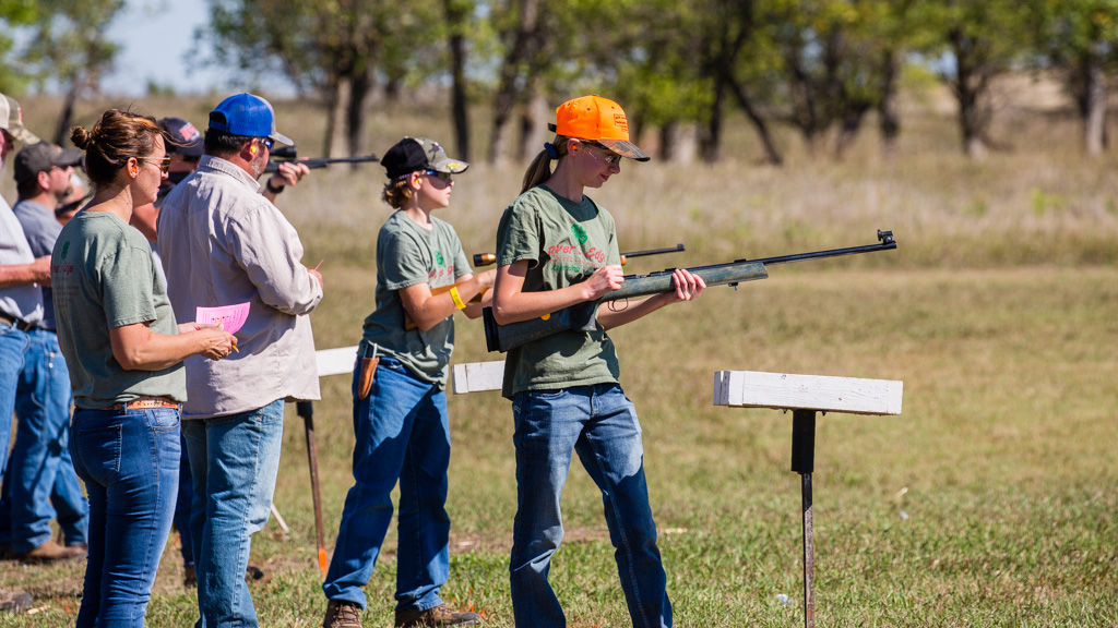Youth shooting rifles from a standing position outdoors