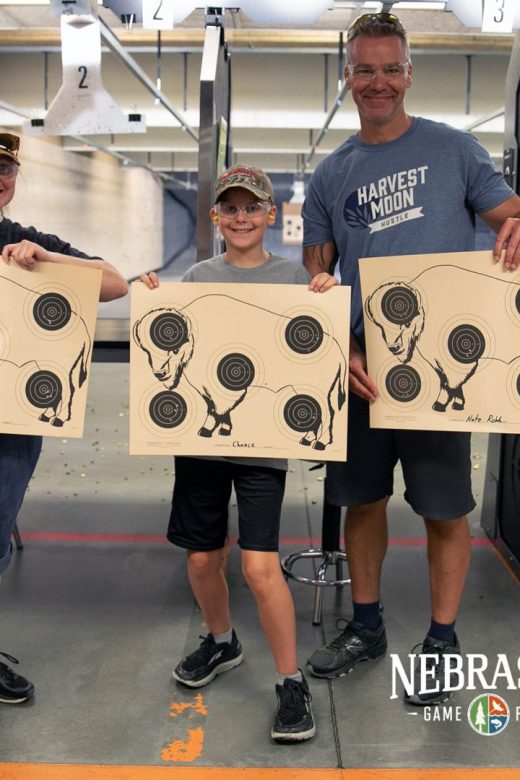 Mom, dad, and boy on rifle range showing off good shots on target