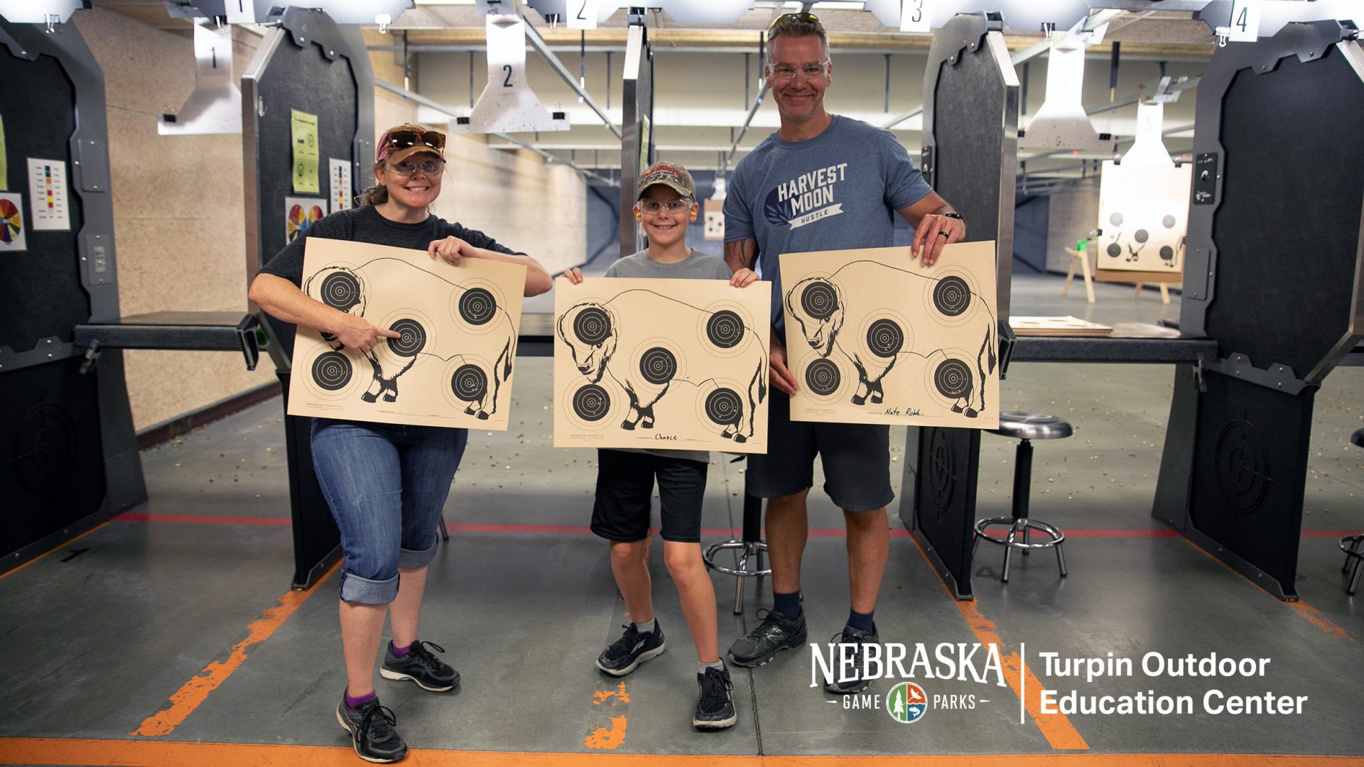 Mom, dad, and boy on rifle range showing off good shots on target