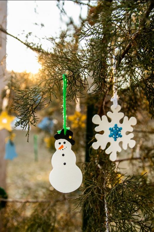 Christmas ornaments hang from a tree in a park.