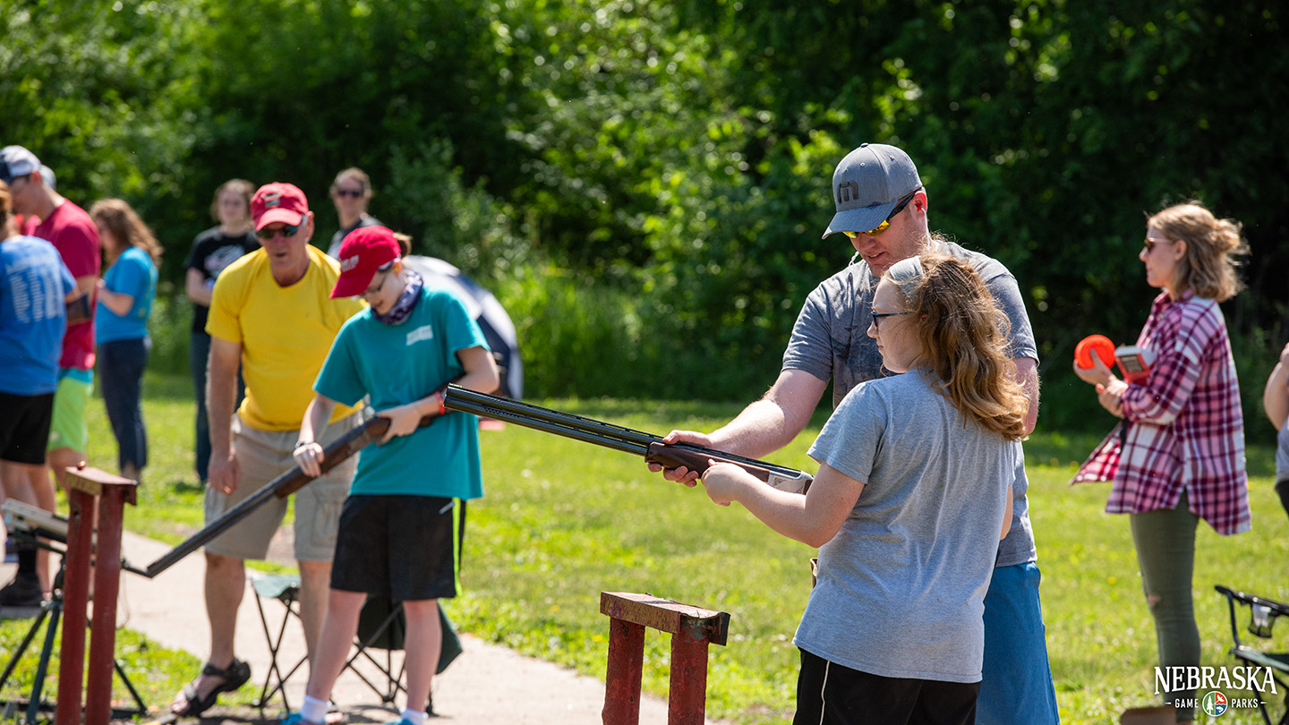 a group of girls practice target shooting clay targets with the help of instructors.