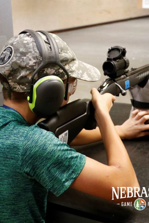 A kid practices target shooting at an indoor range.