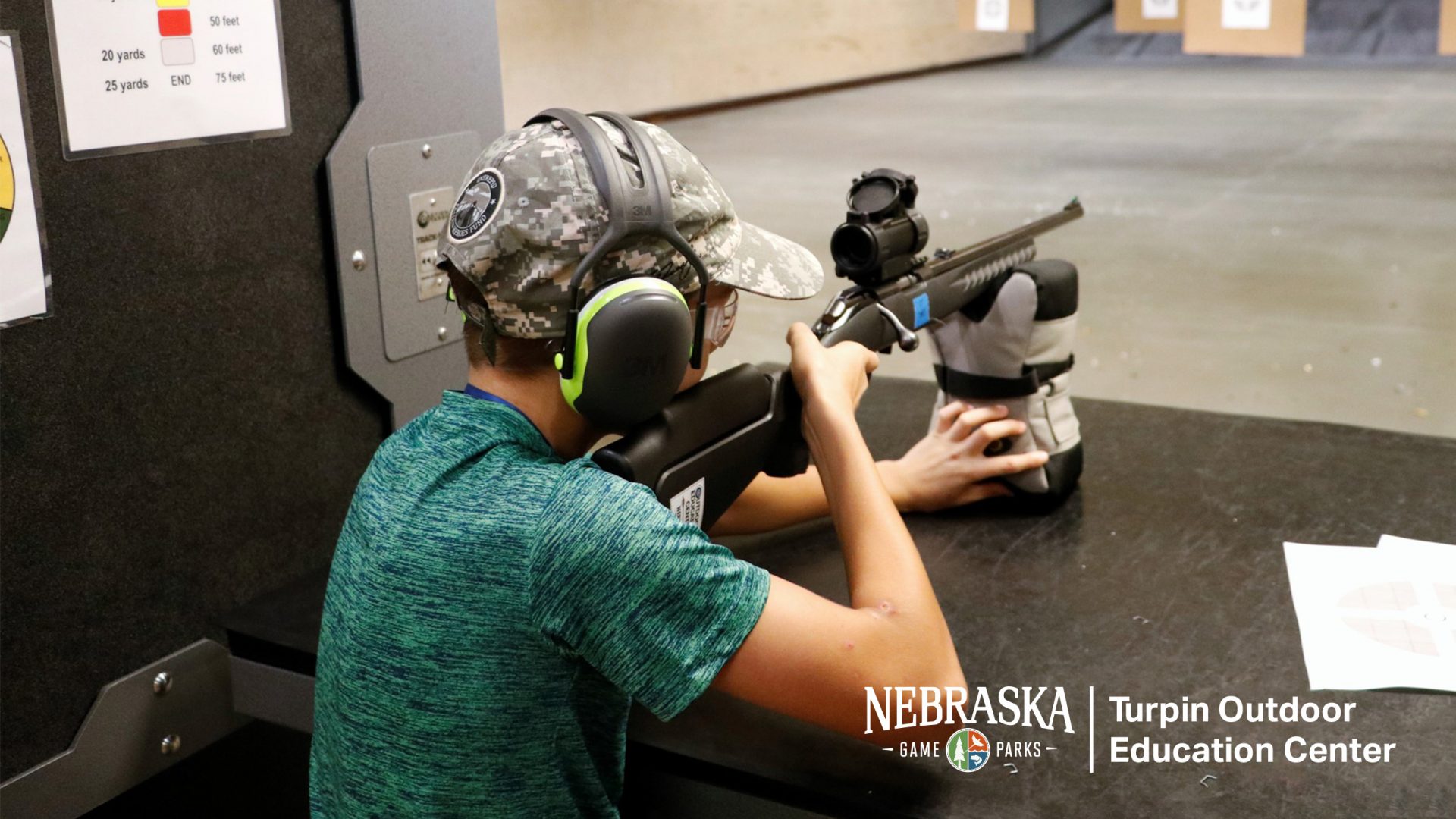 A kid practices target shooting at an indoor range.