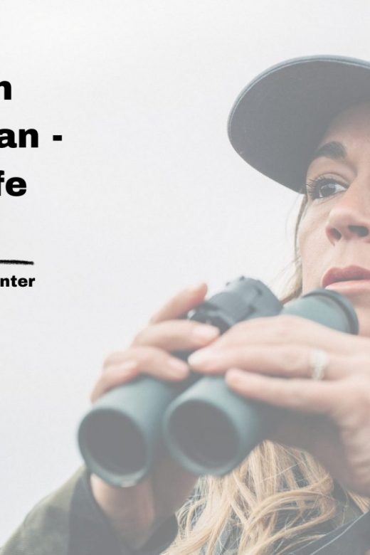 A woman holds binoculars while tracking wildlife.