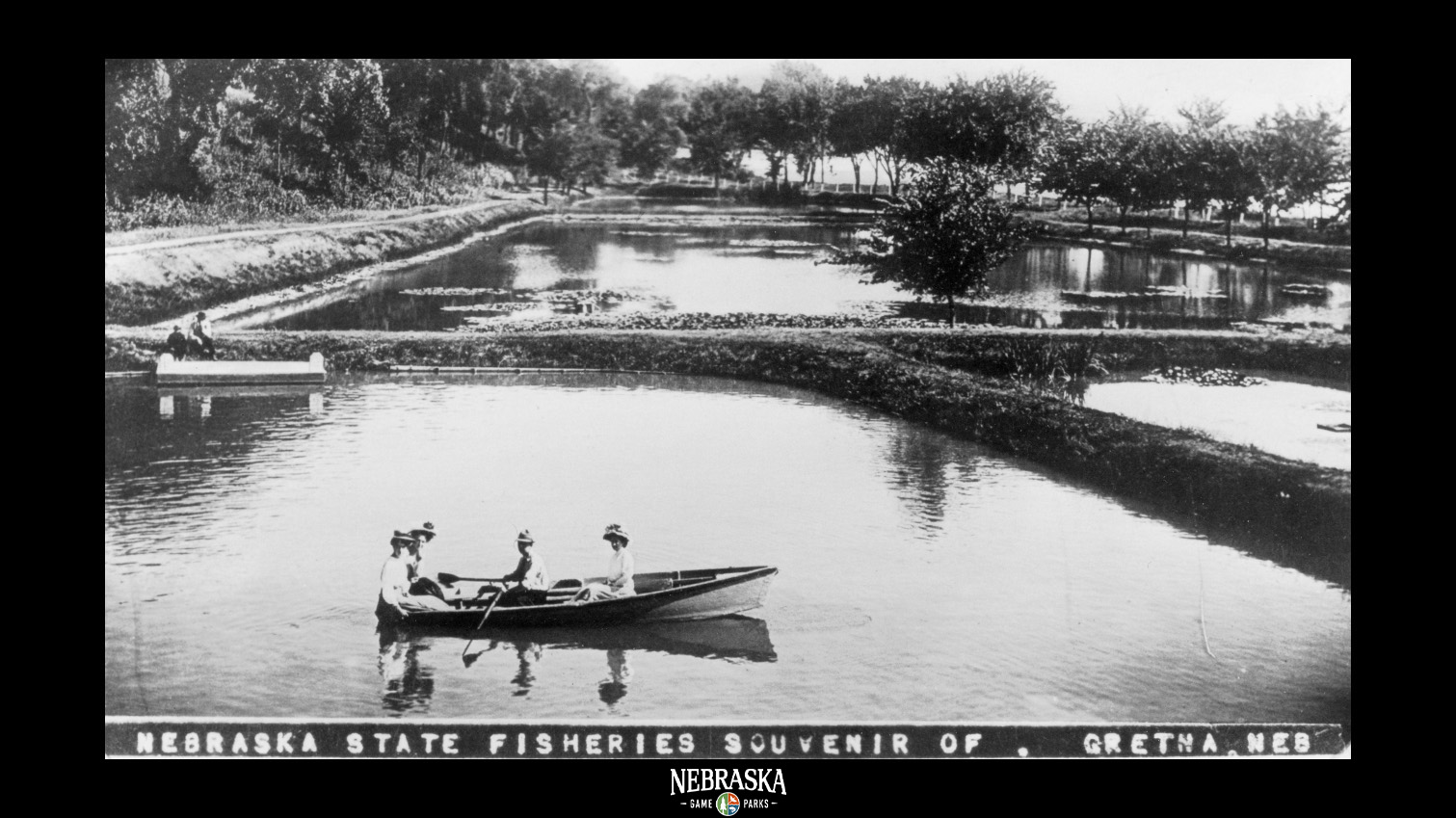 A historic image of people on a small boat in a pond at the Schramm Hatchery in Gretna, Nebraska.