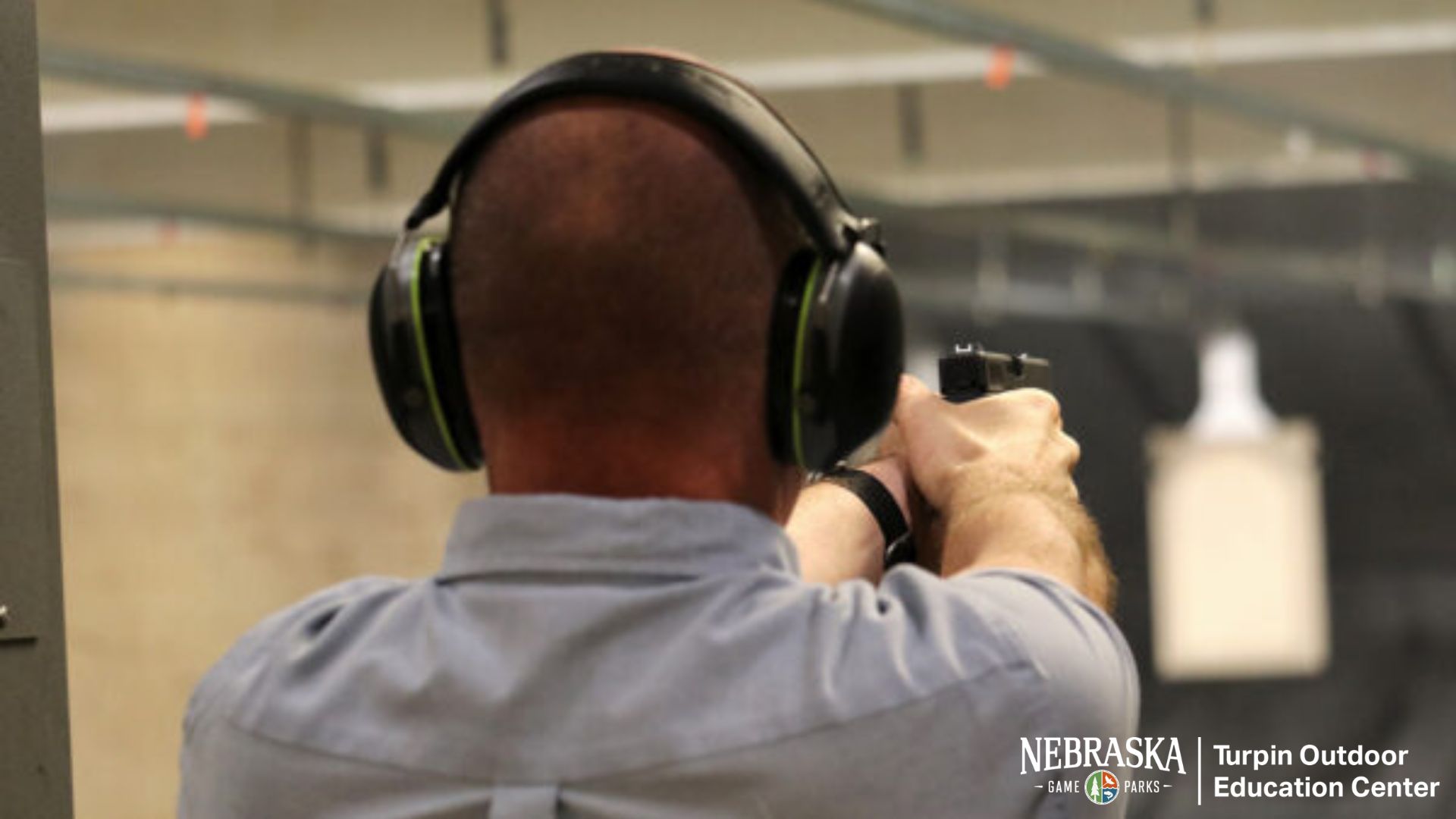 A man practices shooting firearms at an indoor range.