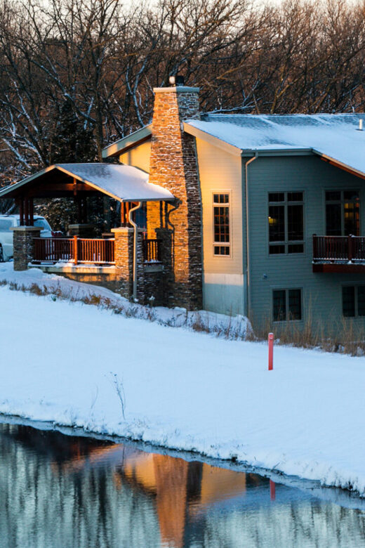 Winter scene of a cabin at Ponca State Park next to a pond.