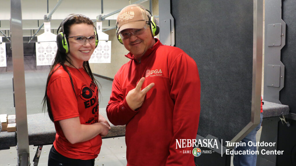 Two people at an indoor shooting range.