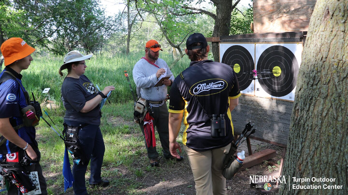 People participating in an outdoor archery competition in a forested area.