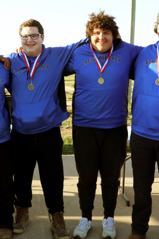 Team of 5 trap competitors from Creighton Prep posing with medals next to Conservation Officer