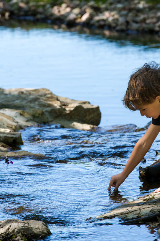 A child plays in Crawdad Creek at Platte River State Park during summertime.