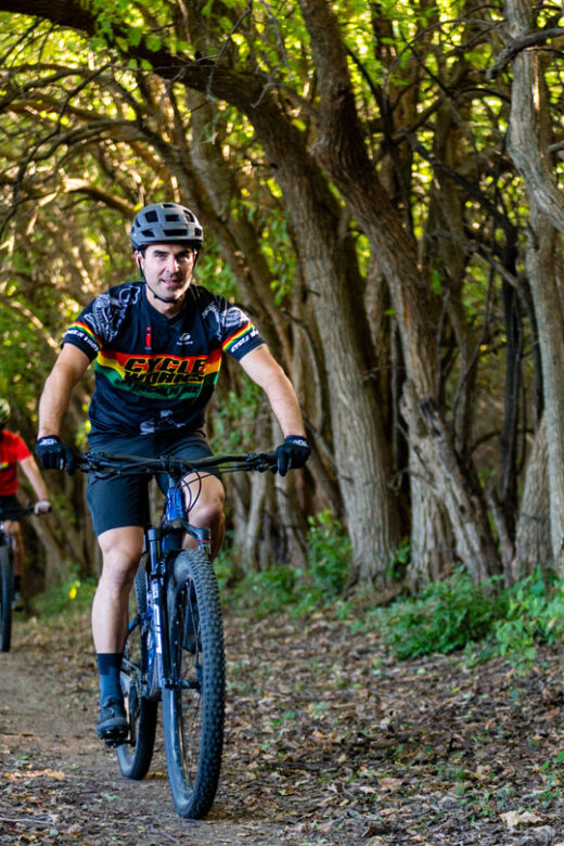 People riding bikes on a forested trail in a park.
