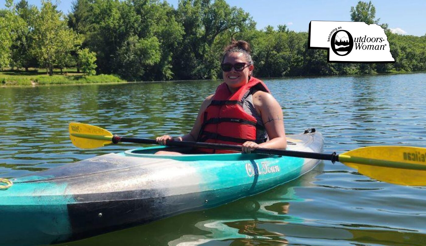 A woman kayaking in a lake wearing a life jacket.