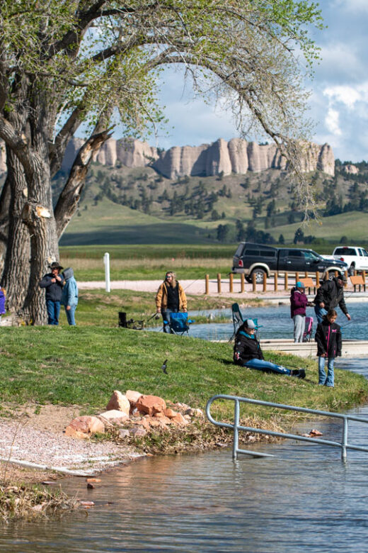 A crowd of people fishes during a fishing derby at Fort Robinson State Park during spring.