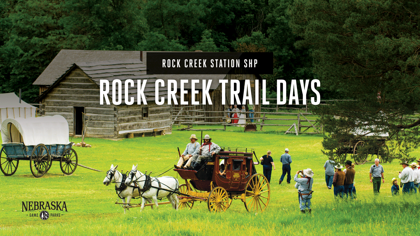 a stagecoach pulls visitors past log buildings and a covered wagon