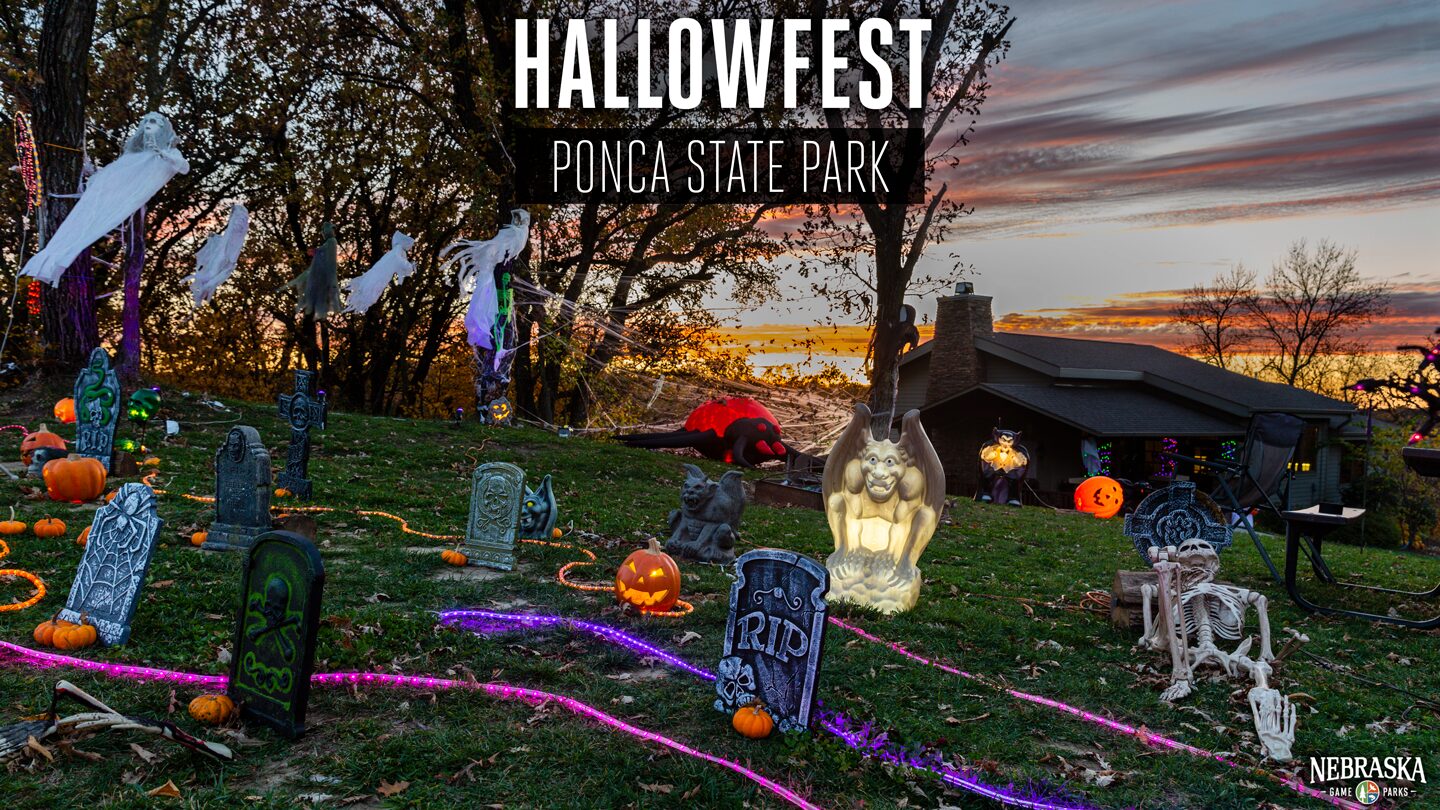 The sun sets in the background of a lawn at Ponca State Park filled with Halloween decor near a cabin.