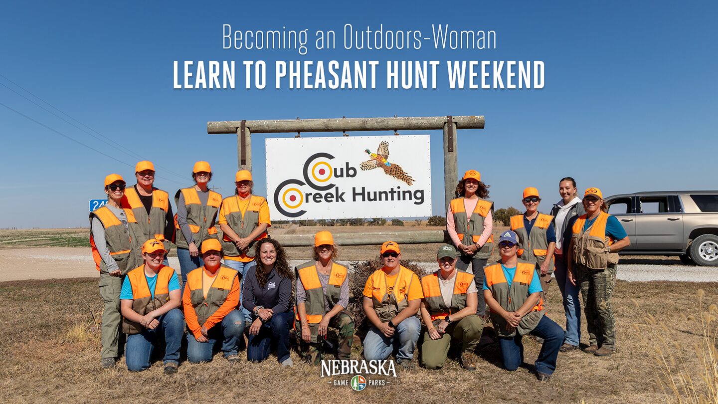 Women in hunting gear pose for a photo in front of a Cub Creek Hunting sign.